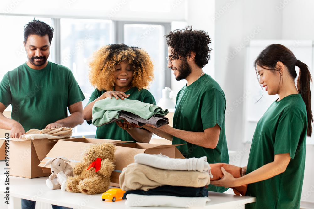 © Syda Productions - charity, donation and volunteering concept - international group of happy smiling volunteers packing clothes and other stuff in boxes at distribution or refugee assistance center