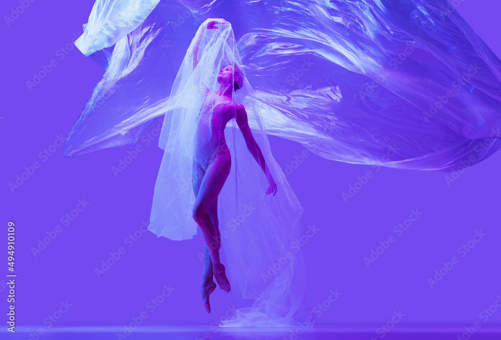 Portrait of beautiful flexible woman, ballerina dancing with cloth on purple studio background in neon. Fashion, style, art, beauty Portrait of beautiful flexible woman, ballerina dancing with cloth on purple studio background in neon. Fashion, style, art, beauty