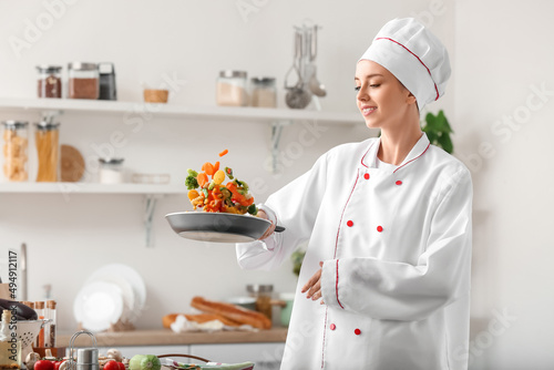 Female chef frying vegetabl...