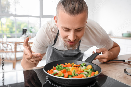 Young man frying vegetables...