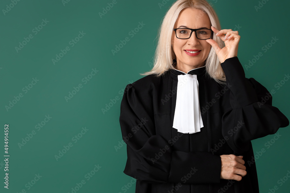 Mature female judge in robe on green background