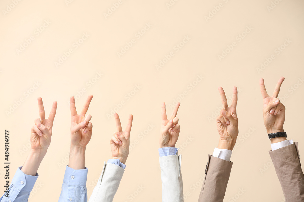 Business people showing victory gesture on beige background