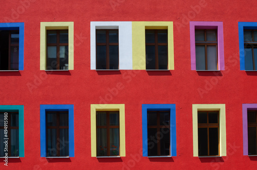 Building in the center of city with red color painted wall and different colors paynted widows.