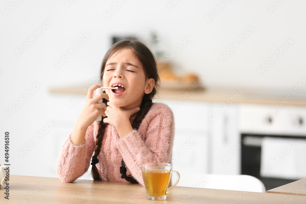 Little girl with sore throat using medical spray in kitchen Little girl with sore throat using medical spray in kitchen