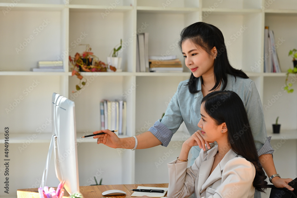 A portrait of happy Asian businesspeople sitting and standing in the office working together on document, computer, for business and technology concept. A portrait of happy Asian businesspeople sitting and standing in the office working together on document, computer, for business and technology concept.
