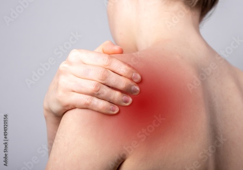 Shoulder pain and trigger points. Naked woman holding painful shoulder with red spot closeup. Joint injuries. Health care  medical treatment concept. High quality photo