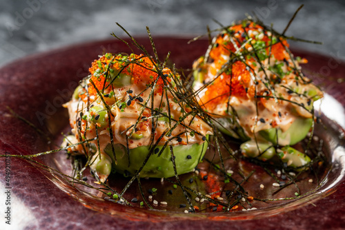 Board with stuffed avocado and micro green on wooden background, closeup