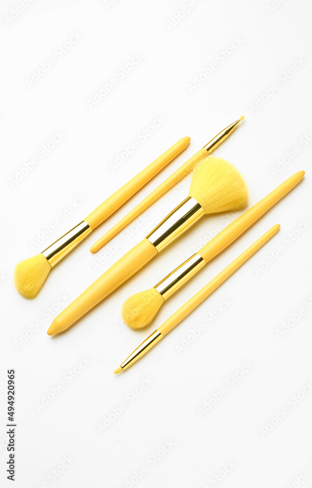Set of yellow makeup brushes on white background