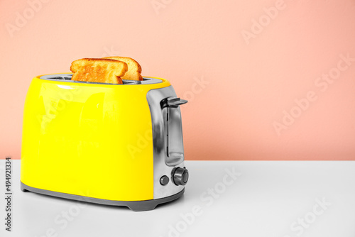 Modern toaster with bread slices on table