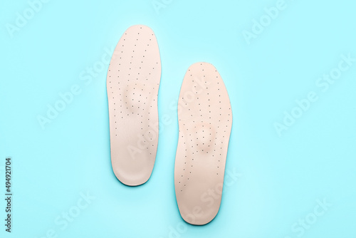Pair of leather orthopedic insoles on blue background