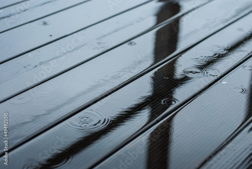 Raindrops fall on a wooden terrace. It's raining heavily. A puddle of water on the floor.
