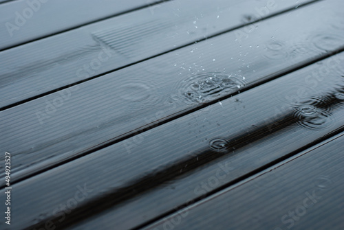 Raindrops fall on a wooden terrace. It's raining heavily. A puddle of water on the floor.