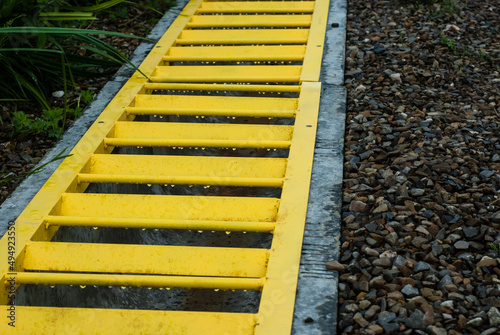 Drainage system for water removal. Yellow metal grate on a concrete gutter. Proper organization of water drainage. Modern sewer.