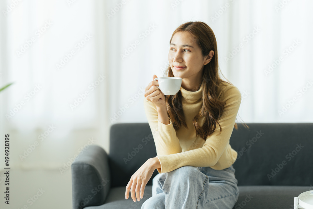 Young asian woman drinking coffee on a sofa bed at home Young asian woman drinking coffee on a sofa bed at home