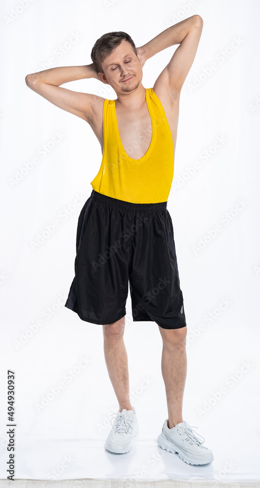 Fototapeta premium fitness man with a thin body, an athlete in black shorts and a yellow t-shirt threw his hands behind his head. The concept of sports motivation for training.