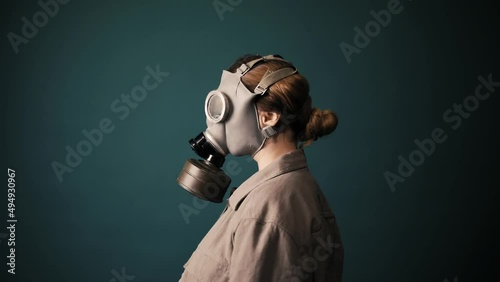 Pouse military in a gas mask, apocalypse, nuclear weapons, atomic explosion of a station, chemical and nuclear weapons protection. Girl in a mask on a green background, war