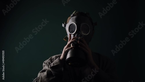 Pouse military in a gas mask, apocalypse, nuclear weapons, atomic explosion of a station, chemical and nuclear weapons protection. Girl in a mask on a green background, war