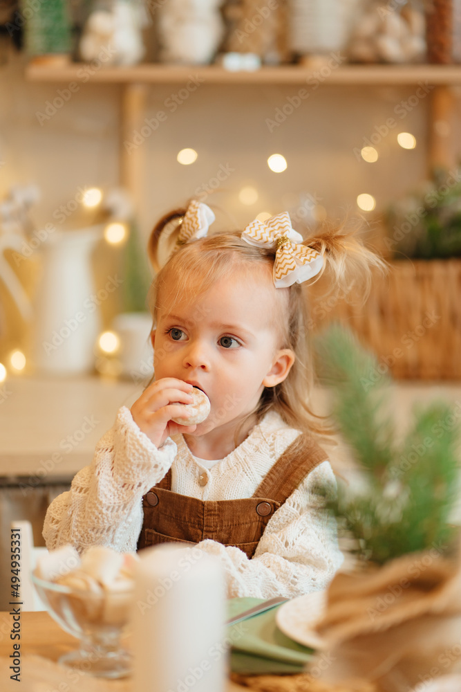 happy beautiful little girl eats gingerbread at the kitchen table. happy beautiful little girl eats gingerbread at the kitchen table.