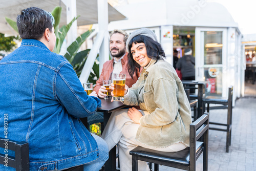 Group of happy friends drinking and toasting beer at brewery bar - Friendship concept with young people having fun together at pub - Focus on middle pint glass