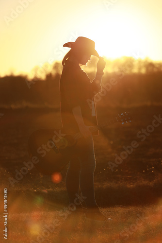 cowgirl with guitar at sunset
