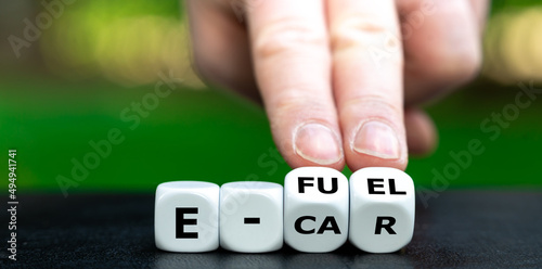 Symbol for using e-fuels. Hand turns dice and changes the expression "e-car" to "e-fuel".