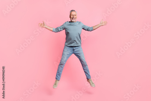Full length body size view of attractive cheerful grey-haired man jumping having fun isolated over pink pastel color background