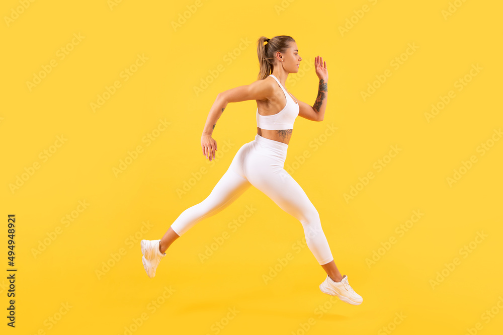 sport woman runner running on yellow background