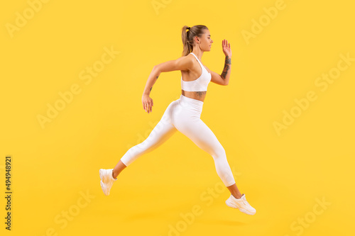 sport woman runner running on yellow background