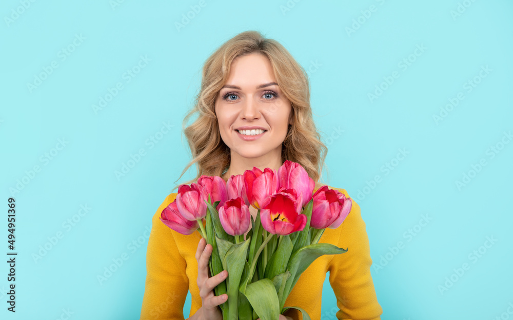 face of happy young woman with spring tulip flowers on blue background