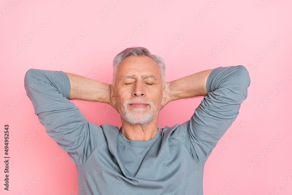 Photo of funny dreamy retired man wear grey shirt arms behind head closed eyes isolated pink color background Photo of funny dreamy retired man wear grey shirt arms behind head closed eyes isolated pink color background