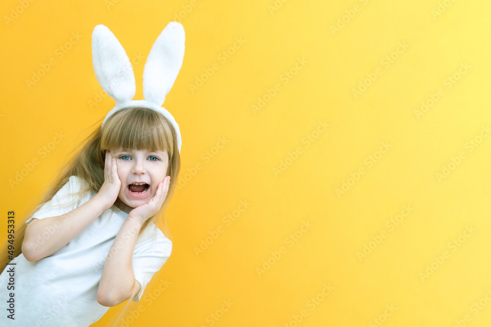 cheerful girl with rabbit ears on her head on a yellow background. Funny crazy happy child. hands a rabbit. Preparation for the Easter holiday. copy space for text cheerful girl with rabbit ears on her head on a yellow background. Funny crazy happy child. hands a rabbit. Preparation for the Easter holiday. copy space for text
