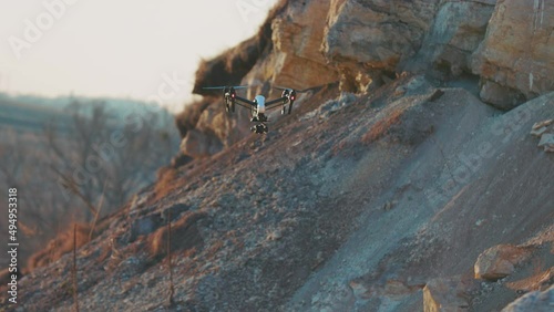 Beautiful view of drone flies on background rock. Modern technologies for shooting photos and videos from above. Golden hour