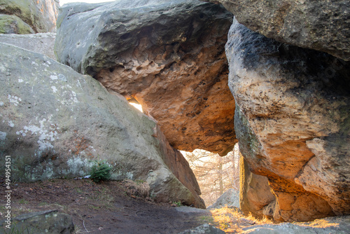 sun shining through a hole between two huge sandstone rocks