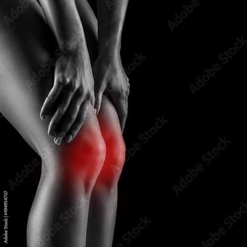 Close-up of a woman feeling pain in her knee and she is massaging her knee. healthcare and medical concept 