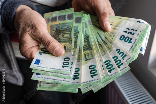 Close up on hands of unknown caucasian senior man holding and counting 100 euro banknotes money wealth insurance payment or lifetime savings copy space photo