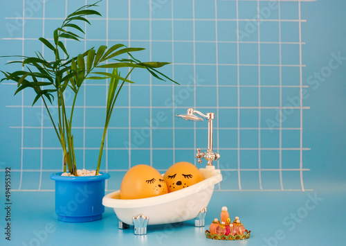 Egg takes a bath in a blue bathroom with a palm tree. Creative Easter photography.
