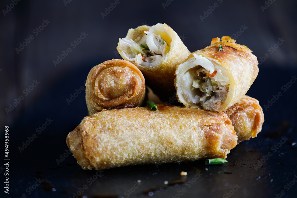 Fresh stack of egg rolls. Top eggroll is broken open to see the ingredients inside. Selective focus with blurred foreground and background. Fresh stack of egg rolls. Top eggroll is broken open to see the ingredients inside. Selective focus with blurred foreground and background.