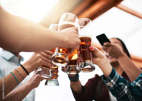 This is how we celebrate. Low angle shot of a group of young unrecognizable business colleagues having a celebratory toast with beer around a table.