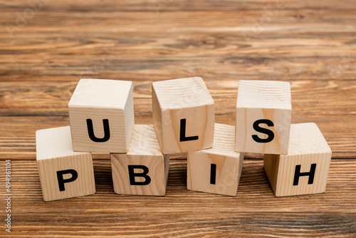 close up view of wooden cubes with black publish inscription on wooden desk.