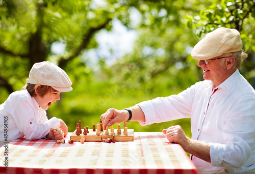 happy grandpa and grandson playing chess in spring garden photo