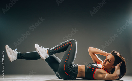 Beautiful slim fit sportswoman training on dark background