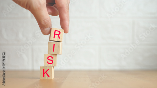 Risk management concept. Hand holding wooden cubes arranged creatively to describe the risk concept with Letters R, I, S, K on cubes. Financial risk assessment, risk reward and portfolio 