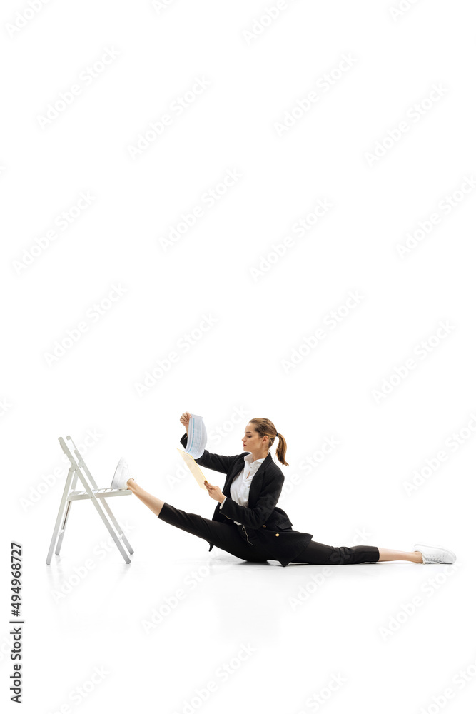 Portrait of young beautiful woman, employee in black suit sitting on twine and reading analytics isolated over white background Portrait of young beautiful woman, employee in black suit sitting on twine and reading analytics isolated over white background