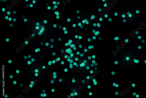 Defocused bokeh lights on black background, an abstract naturally blurred backdrop for Valentines Day or birthday party. Festive light texture. Green blue garland in blur. 