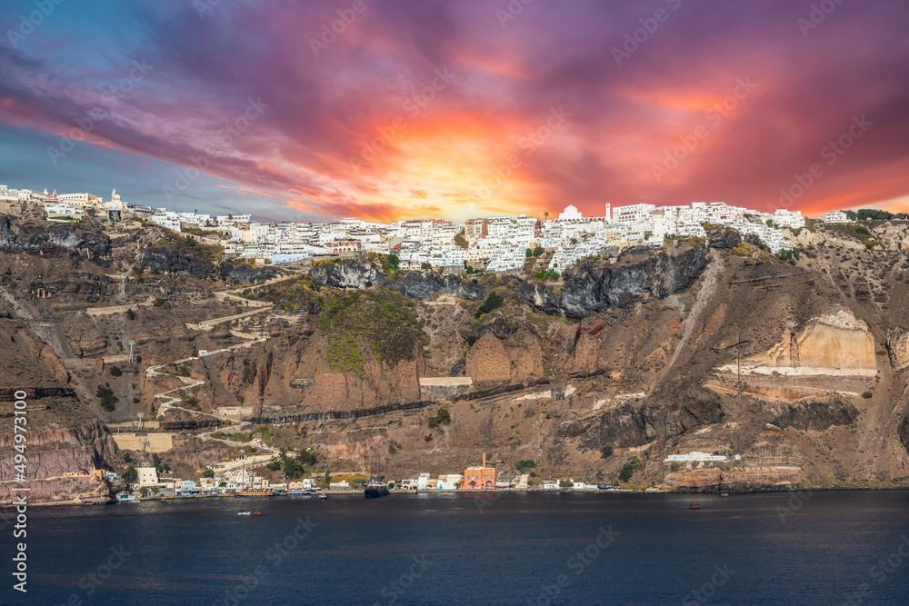 Fira at sunset. Capital of the Greek Aegean Island of Santorini. Panoramic view of Fira from the sea. - obrazy, fototapety, plakaty 