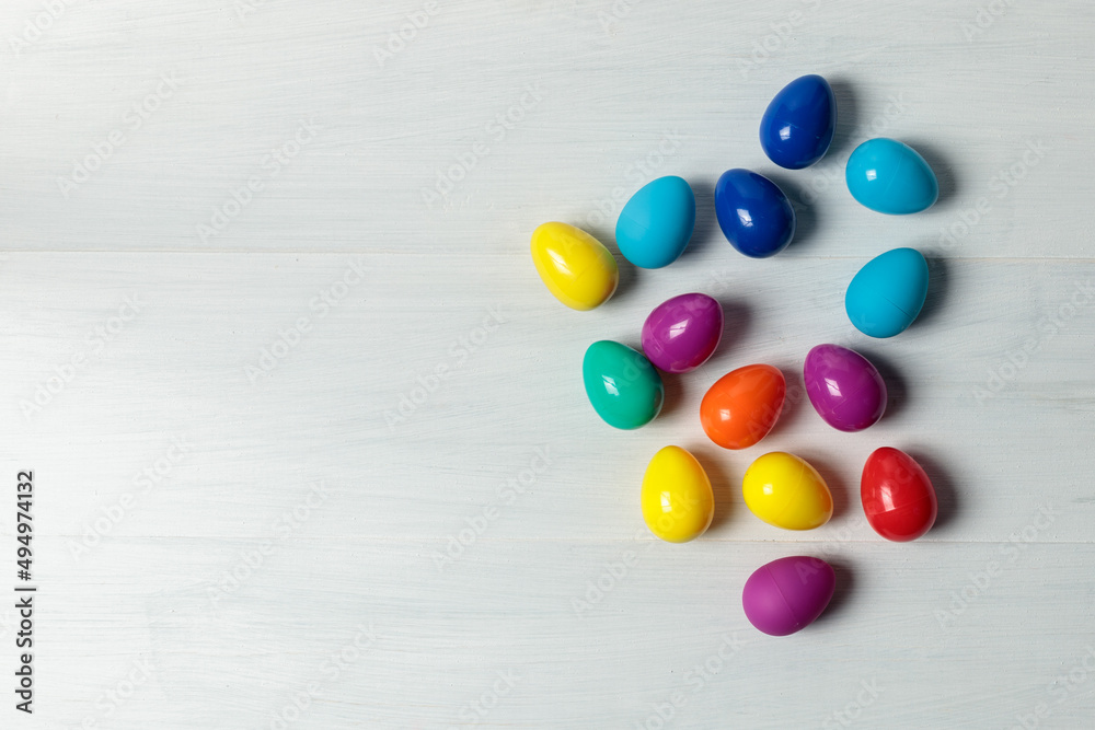 Easter eggs. Toy multicolored plastic Easter eggs on a light wooden background. Top view. Place for text