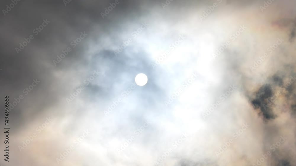 A beautiful circle of the sun behind the clouds passing through the sky