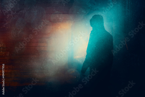 A moody hooded figure, at night, back to camera. Silhouetted against lights. With a neon grunge edit