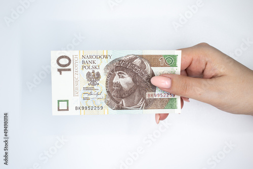 Polish currency held in the hand against a white background 