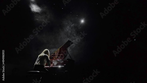 The pianist plays the piano in the backlight